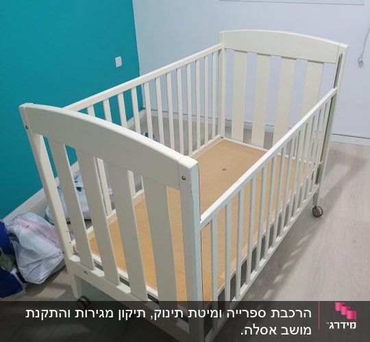 מיטת תינוק על גלגלים בחדר עם קיר טורקיז